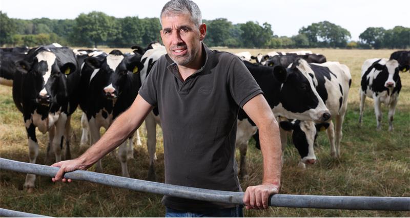 UK dairy farmer in freestall barn at milking, milk price contract crisis 2026